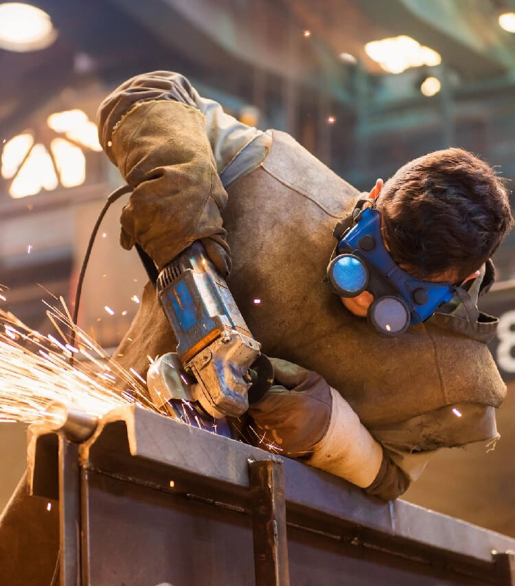 Young man with protective goggles welding in a factory